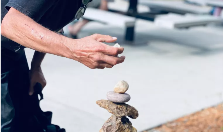 man outside in the process of balancing rocks